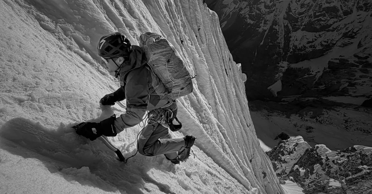 alpiniste solo progressant sur une face enneigée en haute montagne