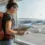 Une voyageuse avec un sac de randonnée consulter une carte près d'une grande fenêtre d'aéroport